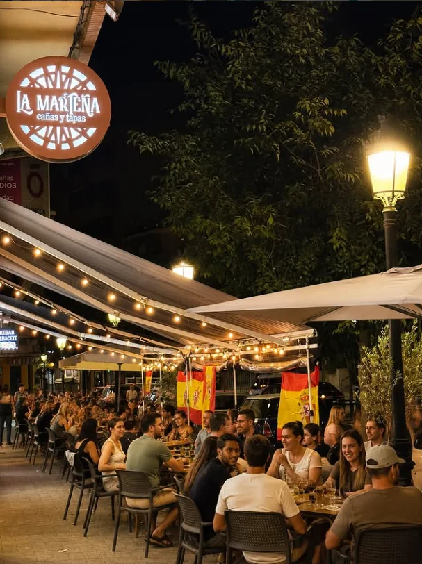 La terraza de La Marteña de noche: el rótulo iluminado, guirnaldas de luces y todas las mesas llenas